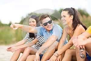 Group of friends pointing somewhere on the beach