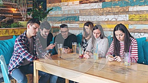 Group of friends at pub ignoring each other in favour of mobile phone