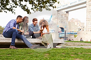 Group Of Friends Relaxing By Tower Bridge In London