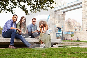 Group Of Friends Relaxing By Tower Bridge In London