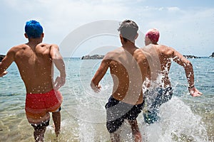 Group of friends running at the beach in to the water having fun and enjoying tehir vacations and holiday at summer - summer time