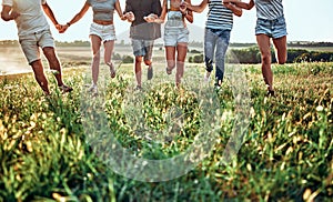 Group of friends running on grass meadow on country side