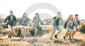 Group of friends running on grass meadow on country side - Happy friendship and freedom concept with young millenial people moving