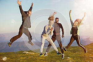 Group of friends running happily together in the grass and jumping