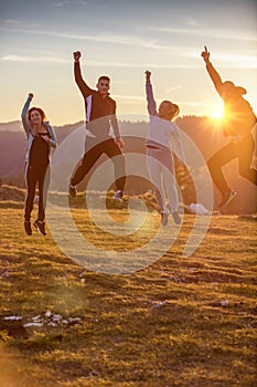 Group of friends running happily together in the grass and jumping