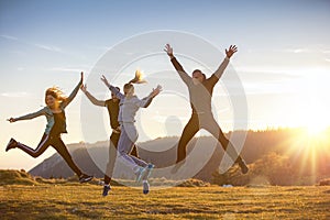 Group of friends running happily together in the grass and jumping