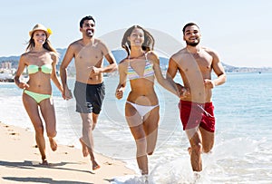 Group of friends running on sand at beach