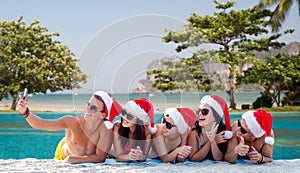 Group of friends in santa hats with smartphone