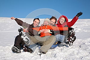 Group of friends sit on plastic sled