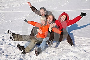 Group of friends sit on plastic sled