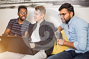 Group of friends sitting on sofa with laptop