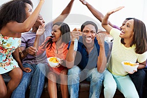 Group Of Friends Sitting On Sofa Watching TV Together