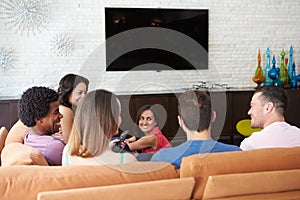 Group Of Friends Sitting On Sofa Watching TV Together