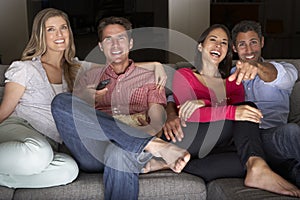 Group Of Friends Sitting On Sofa Watching TV Together