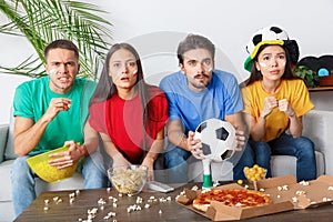 Group of friends sport fans watching concentrated match in colorful shirts