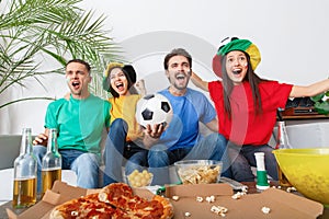 Group of friends sport fans watching match in colorful shirts victory congratulations