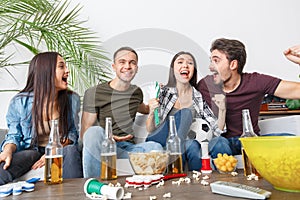 Group of friends sport fans watching soccer match hugging cheerful