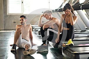 group of friends sport people tired taking a break from running or exercise sitting on treadmill machine in fitness gym. over