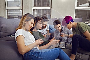 A group of friends of students in leisure with a laptop in a roo