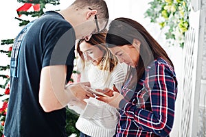 Group of friends such as two girls and man looking at mobile phones and chatting