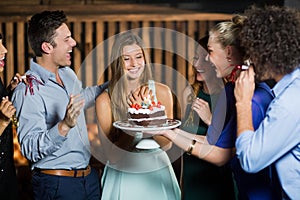 Group of friends surprising a woman with birthday cake