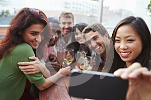 Group Of Friends Taking Photograph At Outdoor Rooftop Bar