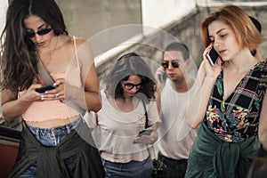 Group of friends talk on smartphones while standing on escalator