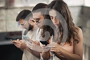 Group of friends talk on smartphones while standing on escalator