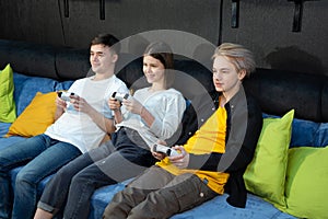 Group of friends of teenagers, boys and girls playing video games on a console in a game club