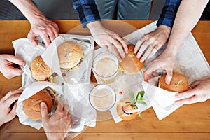 Group of friends toasting beer glasses and eating at fast food - Happy people partying and eating in home garden - Young