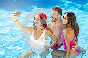 Group of friends together in the swimming pool taking selfie