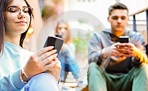 Group of friends using cellphones - Students sitting in a stairs and typing on the smartphones