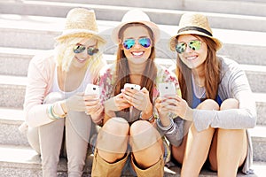 Group of friends using smartphones in the city