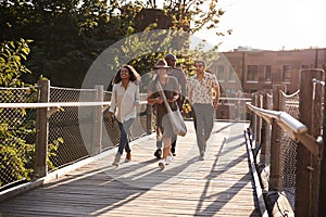 Group Of Friends Walking Along Bridge In Urban Setting