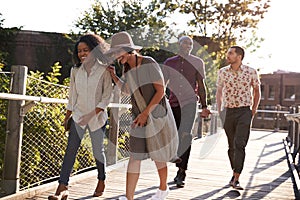 Group Of Friends Walking Along Bridge In Urban Setting