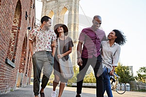 Group Of Friends Walking By Brooklyn Bridge In New York City