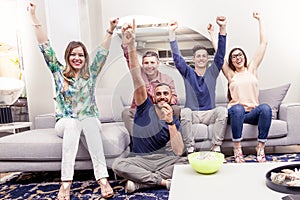Group of friends watching a football match on tv on the couch