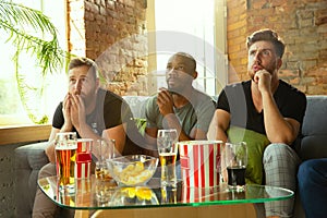 Group of friends watching football or soccer game on TV at home