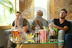 Group of friends watching football or soccer game on TV at home