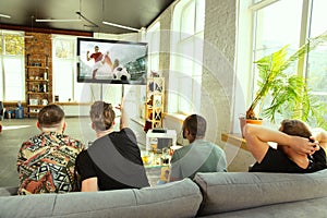 Group of friends watching football or soccer game on TV at home