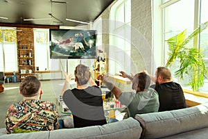 Group of friends watching football or soccer game on TV at home
