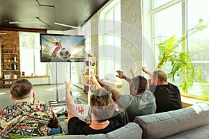 Group of friends watching football or soccer game on TV at home