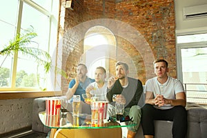 Group of friends watching football or soccer game on TV at home