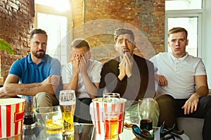 Group of friends watching football or soccer game on TV at home