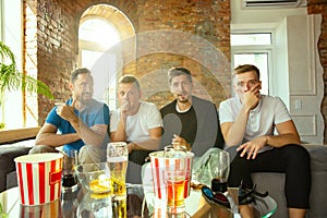 Group of friends watching football or soccer game on TV at home