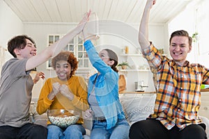 Group of friends watching sport match soccer football game on tv. Happy football fans celebrating victory at home