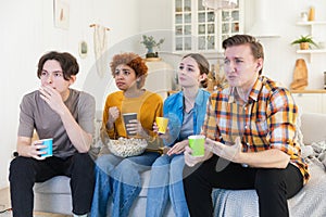 Group of friends watching sport match soccer football game on tv at home. Football fans disappointed missing goal