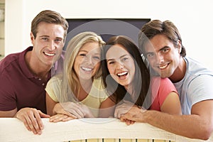 Group Of Friends Watching Widescreen TV At Home