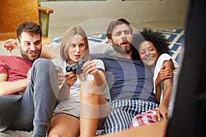 Group Of Friends Wearing Pajamas Playing Video Game Together