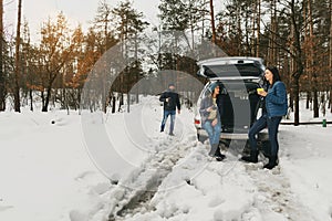 Group friends winter wear snowy winter forest talk drinking coffee car